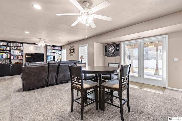 dining area featuring a wealth of natural light, french doors, light carpet, and a textured ceiling