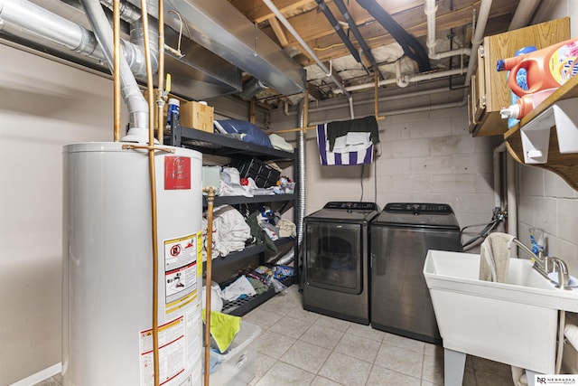 laundry area featuring independent washer and dryer, a sink, water heater, concrete block wall, and laundry area