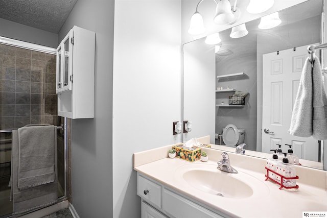 full bathroom with vanity, toilet, a shower stall, and a textured ceiling