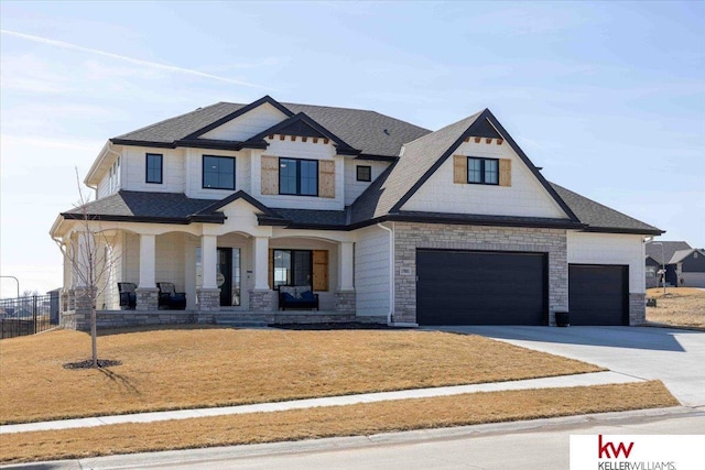 view of front of property with a front yard, driveway, roof with shingles, covered porch, and stone siding