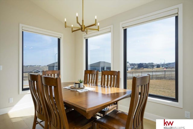 dining room featuring baseboards, an inviting chandelier, and vaulted ceiling