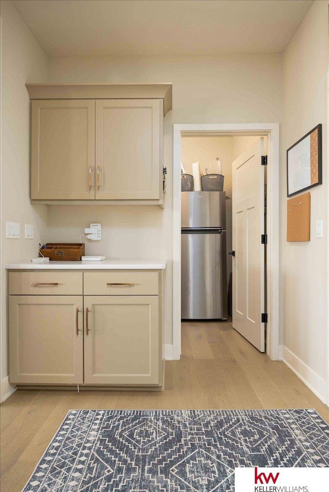 kitchen featuring baseboards, light countertops, freestanding refrigerator, and light wood-style floors