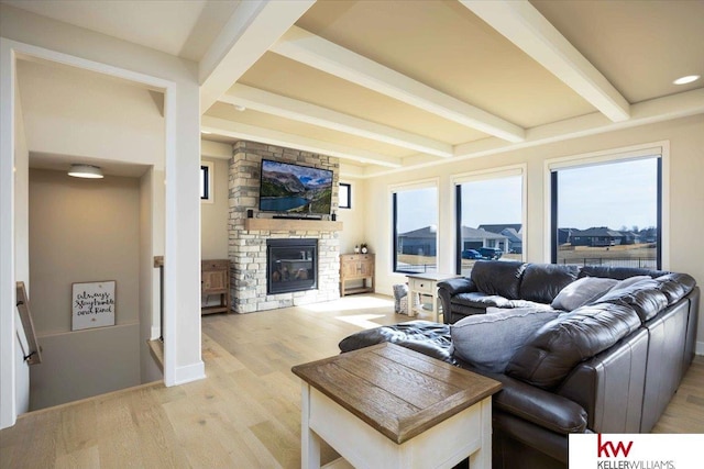 living area with a fireplace, beamed ceiling, and light wood-style floors