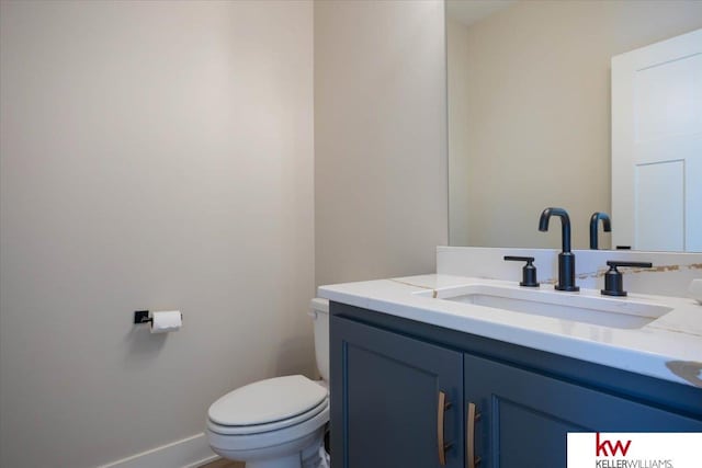 bathroom featuring toilet, vanity, and baseboards