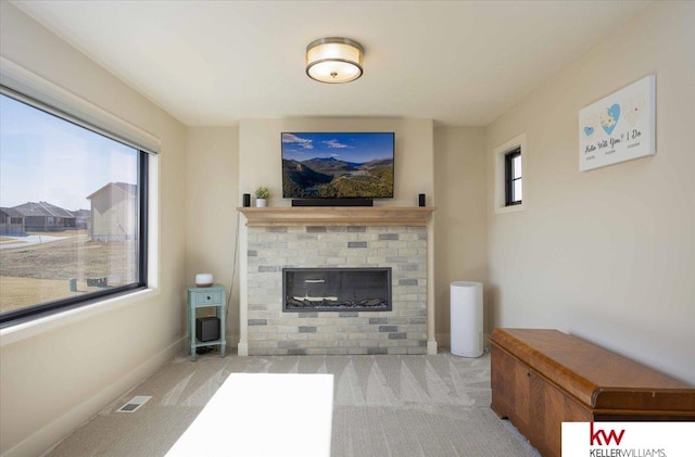 living room with a brick fireplace, a healthy amount of sunlight, visible vents, and carpet floors