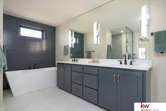 bathroom with a soaking tub, double vanity, marble finish floor, and a sink