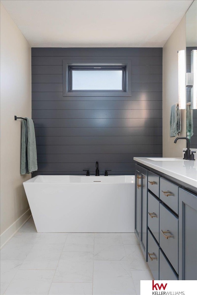 bathroom with vanity, a soaking tub, baseboards, and marble finish floor