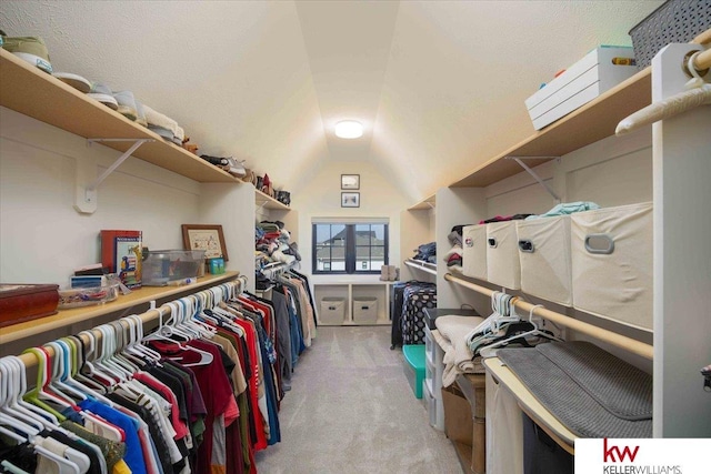 walk in closet with light carpet and vaulted ceiling