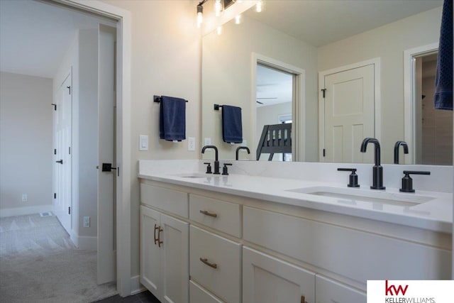 full bathroom featuring a sink, baseboards, and double vanity