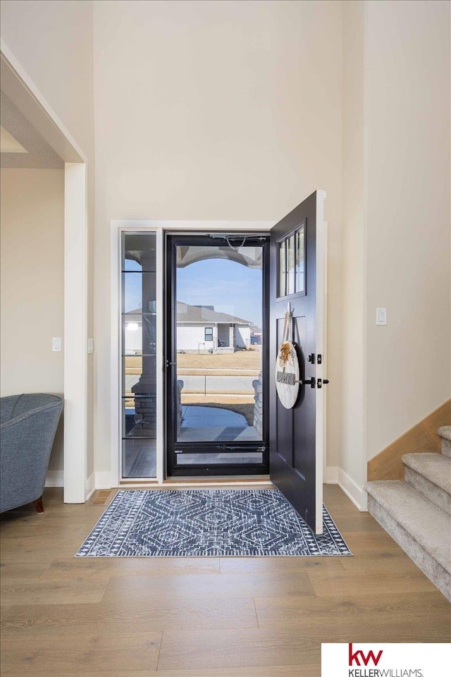 foyer with a towering ceiling, baseboards, wood finished floors, and stairs