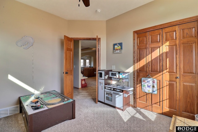 interior space with visible vents, baseboards, light colored carpet, and a ceiling fan