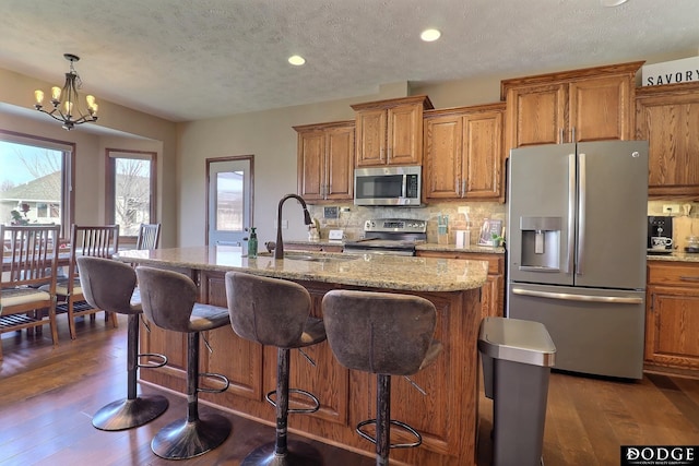 kitchen with tasteful backsplash, brown cabinets, appliances with stainless steel finishes, and a sink