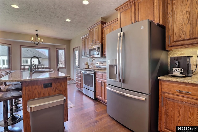 kitchen featuring dark wood-style floors, brown cabinets, stainless steel appliances, and a sink