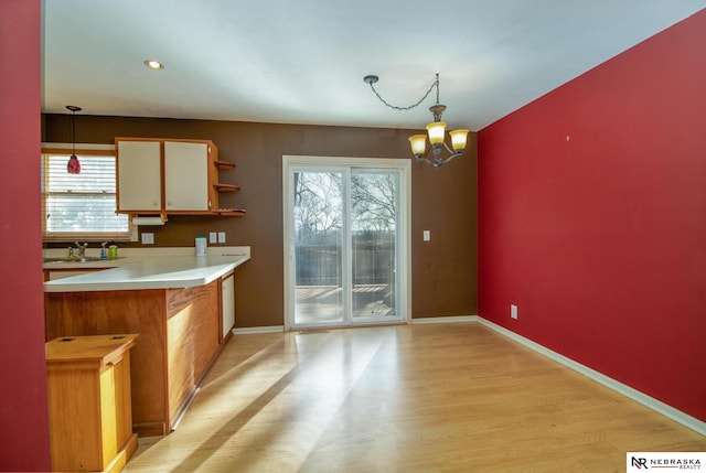 kitchen with baseboards, a notable chandelier, light countertops, and hanging light fixtures