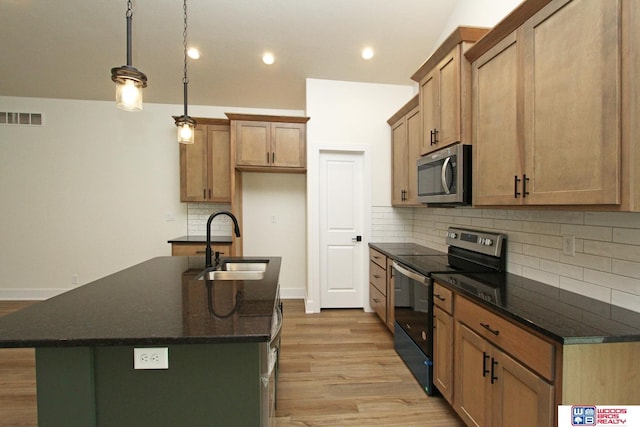 kitchen with visible vents, light wood-style flooring, an island with sink, a sink, and appliances with stainless steel finishes