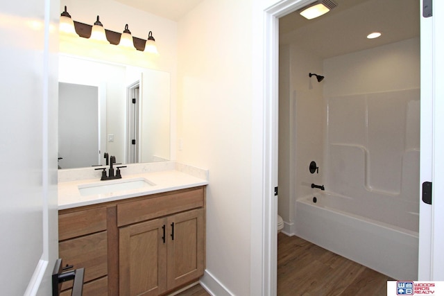 bathroom featuring toilet, wood finished floors, recessed lighting,  shower combination, and vanity