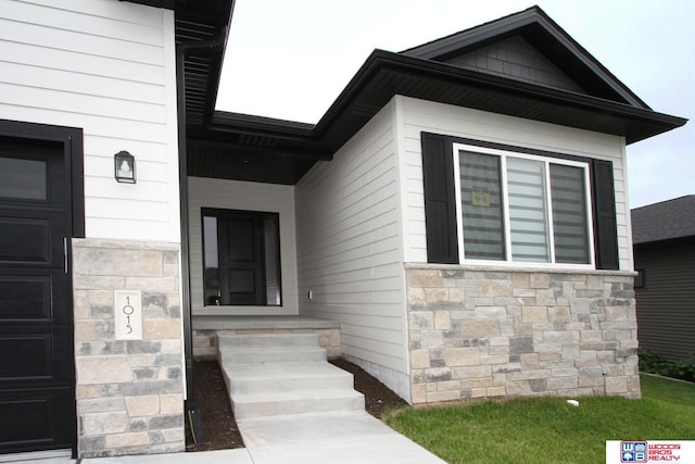 property entrance featuring stone siding and a garage