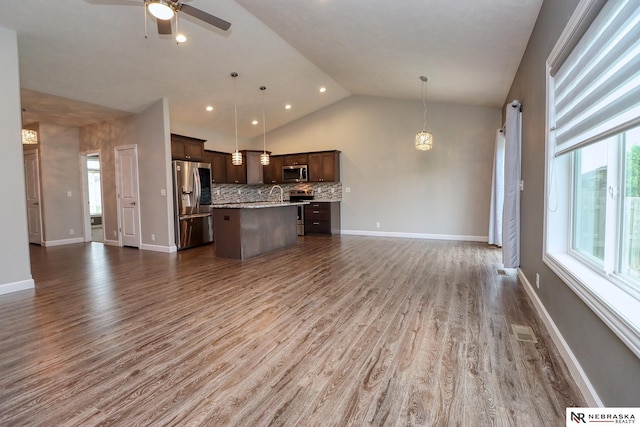 kitchen featuring stainless steel appliances, dark brown cabinetry, a healthy amount of sunlight, and open floor plan