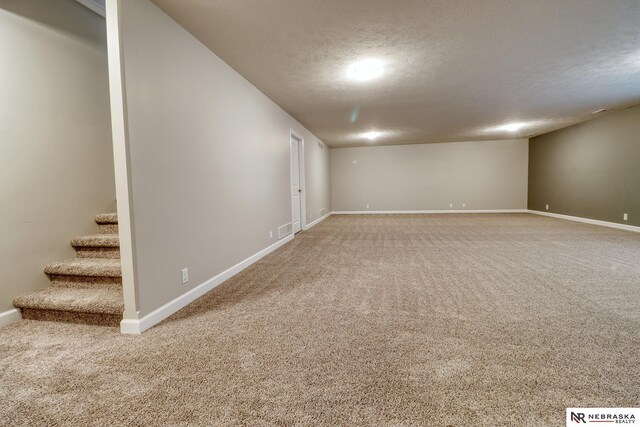 basement with baseboards, stairway, a textured ceiling, and carpet