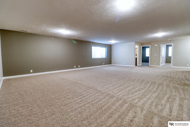 unfurnished room with a textured ceiling, baseboards, and carpet floors