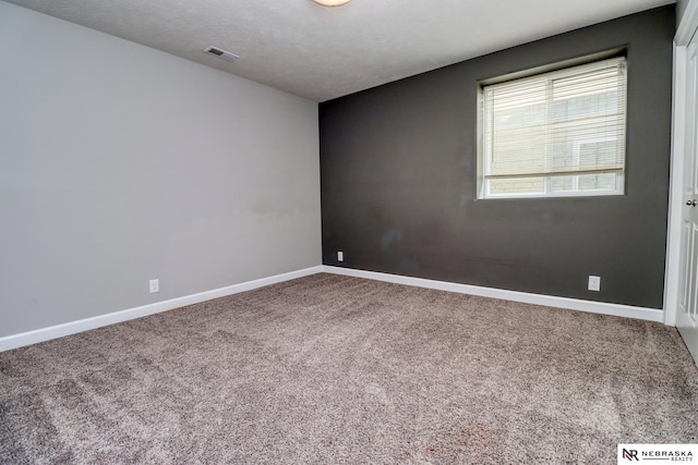 carpeted spare room with visible vents, a textured ceiling, and baseboards