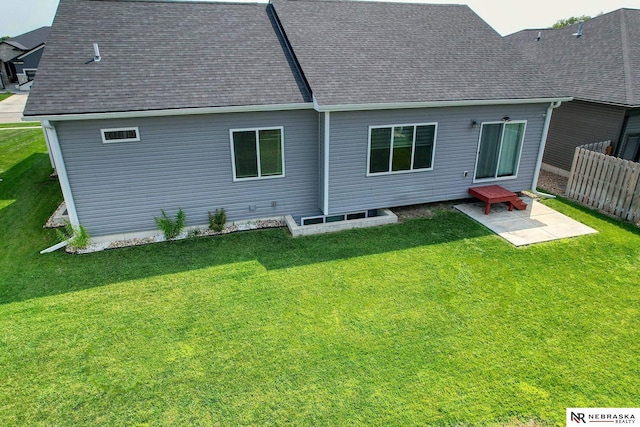 rear view of house with a patio, roof with shingles, a yard, and fence