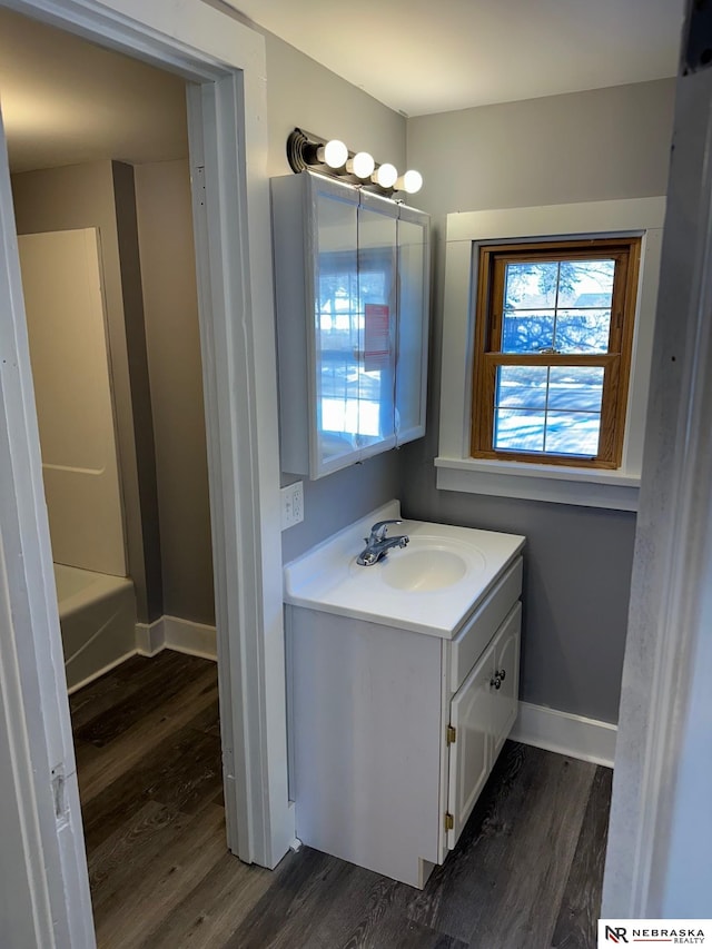 full bathroom with baseboards, wood finished floors, and vanity