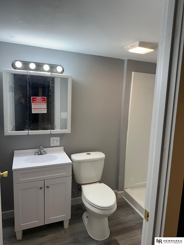 full bathroom featuring baseboards, toilet, wood finished floors, and vanity