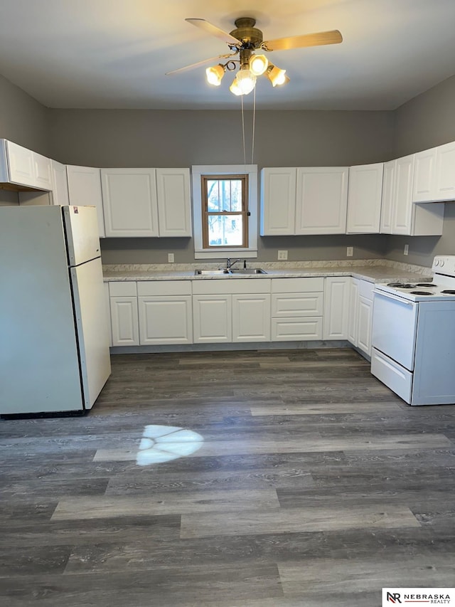 kitchen with white appliances, dark wood-style flooring, a sink, light countertops, and white cabinetry