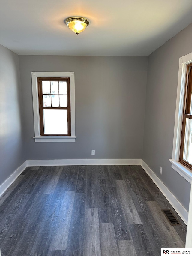 empty room with visible vents, baseboards, and dark wood-style flooring