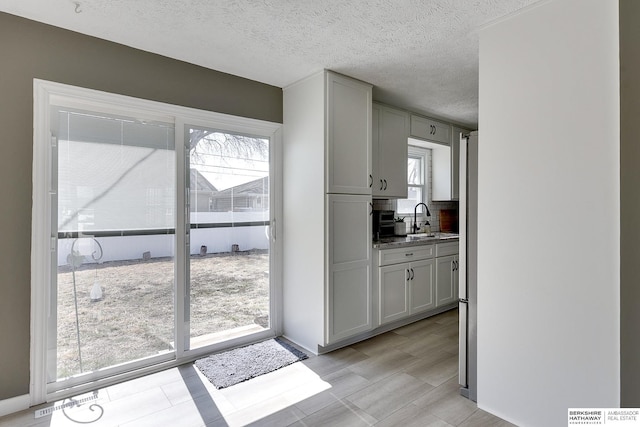 kitchen featuring a textured ceiling, gray cabinetry, and a sink