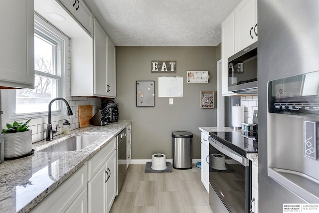 kitchen with a sink, white cabinetry, stainless steel appliances, decorative backsplash, and baseboards