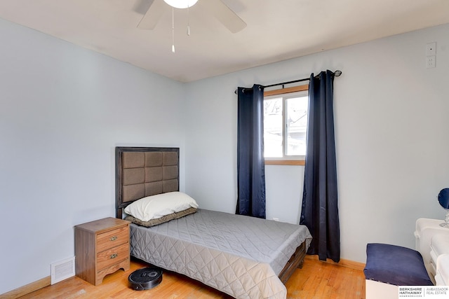 bedroom with ceiling fan, light wood-style floors, visible vents, and baseboards