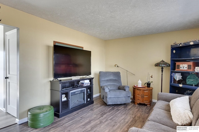 living room featuring a textured ceiling, baseboards, and wood finished floors