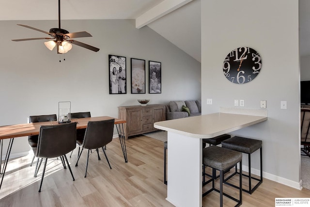 dining space featuring lofted ceiling with beams, light wood-type flooring, baseboards, and ceiling fan