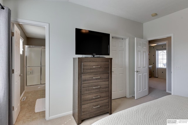 bedroom featuring visible vents, baseboards, light carpet, and ensuite bath