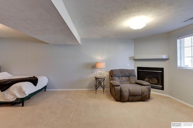 sitting room featuring a glass covered fireplace, carpet flooring, baseboards, and visible vents