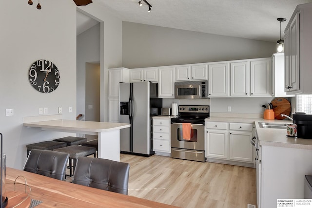 kitchen with light wood-type flooring, a sink, white cabinetry, appliances with stainless steel finishes, and light countertops