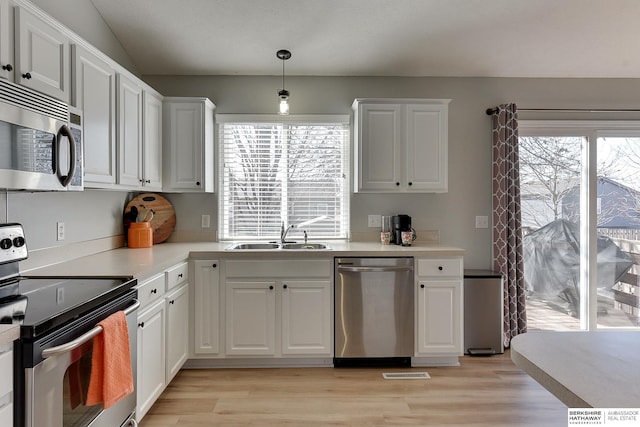 kitchen featuring white cabinets, light wood finished floors, appliances with stainless steel finishes, and a sink