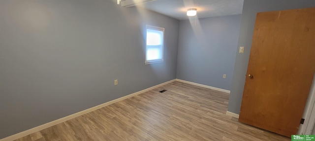 unfurnished room featuring light wood-style flooring, visible vents, and baseboards