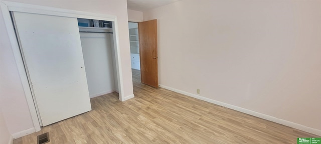 unfurnished bedroom with a closet, visible vents, light wood-style flooring, and baseboards