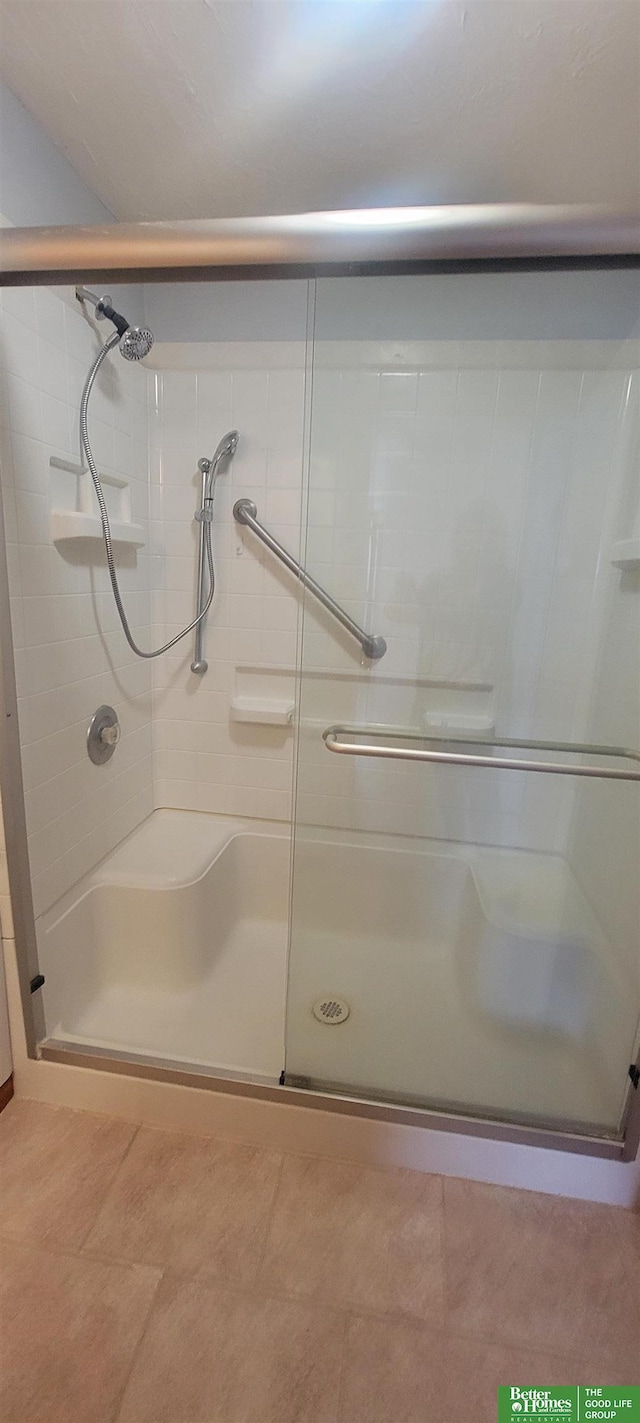 bathroom with a shower stall and tile patterned floors