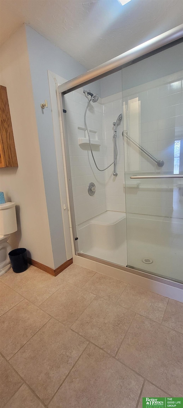 bathroom with a shower stall and baseboards