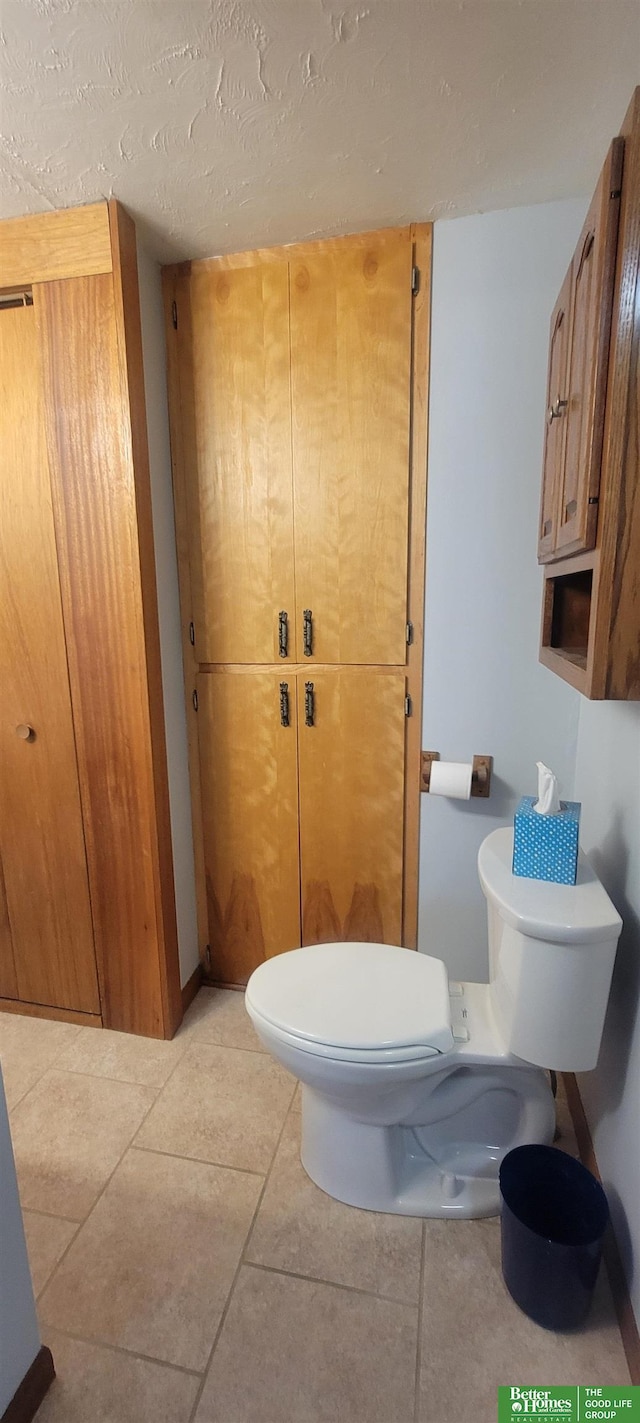 bathroom with tile patterned floors, toilet, and a textured ceiling