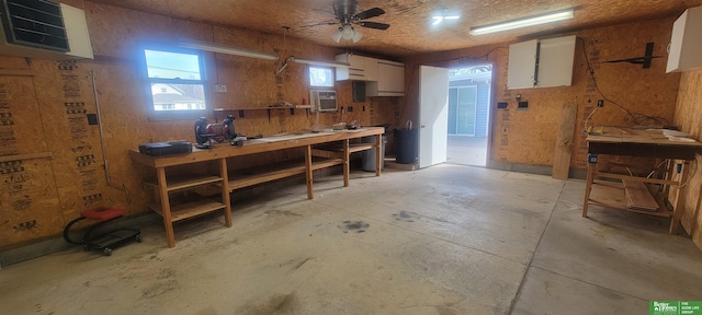 miscellaneous room with a workshop area, concrete flooring, and a ceiling fan