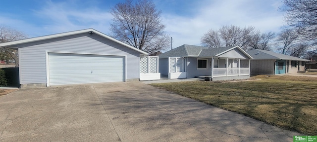 ranch-style home with covered porch, a detached garage, a front lawn, and roof with shingles