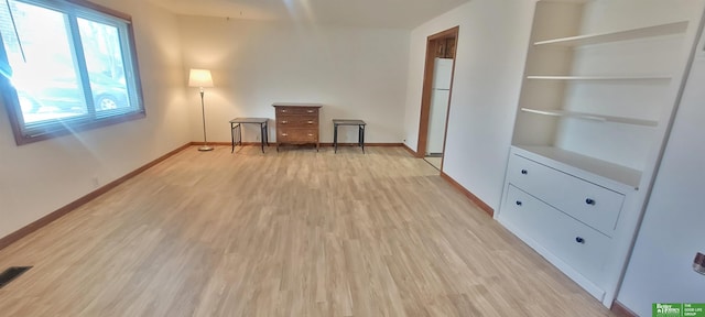 empty room with visible vents, light wood-style flooring, and baseboards