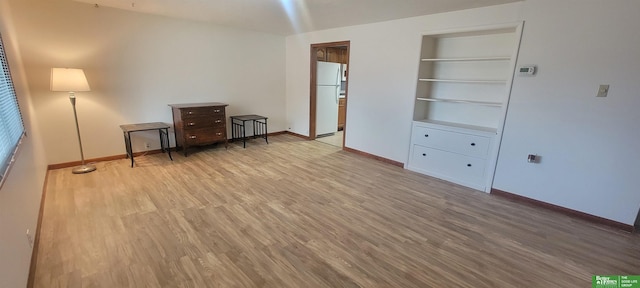 unfurnished bedroom featuring light wood-style flooring, baseboards, and freestanding refrigerator