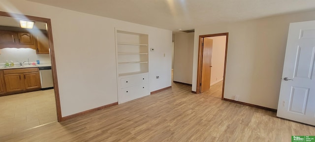 bedroom with connected bathroom, light wood-style floors, baseboards, and a sink