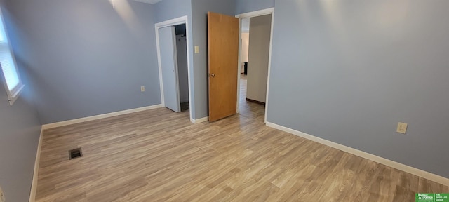 unfurnished bedroom featuring visible vents, light wood-style flooring, and baseboards